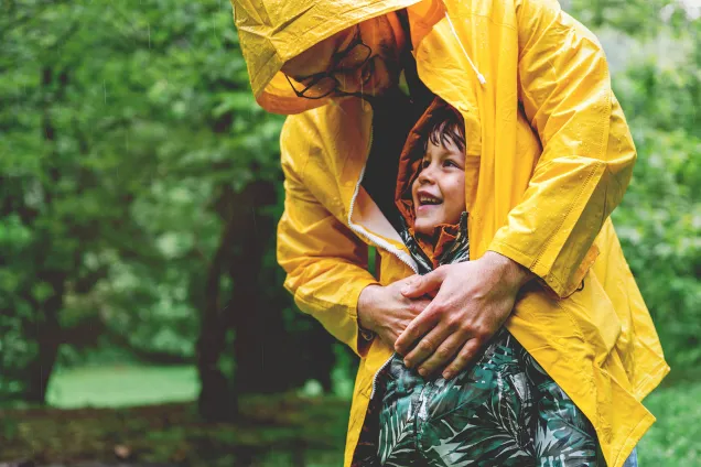 vader beschermt kind tegen regen met zijn jas