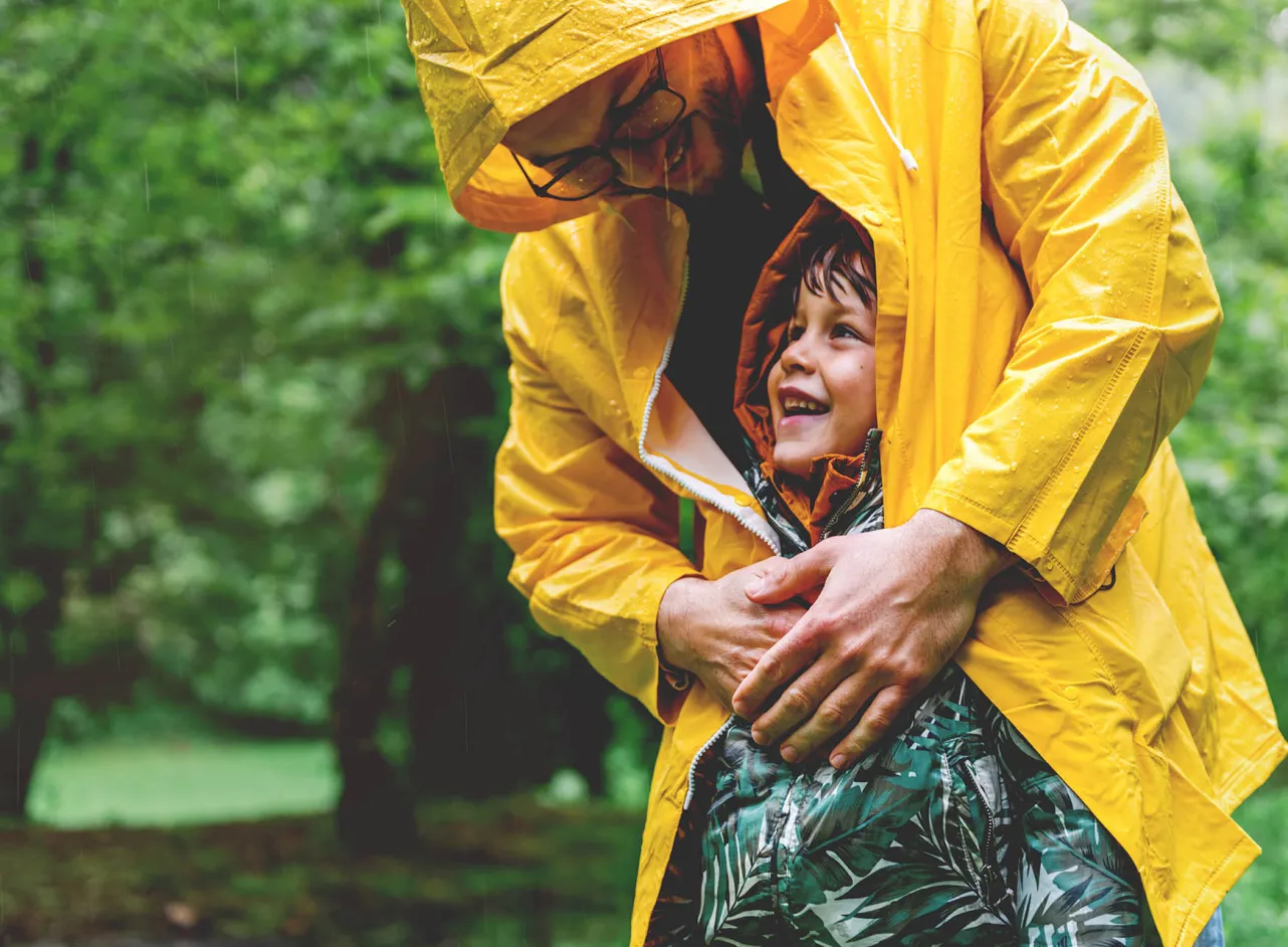 papa protège l'enfant de la pluie avec son manteau